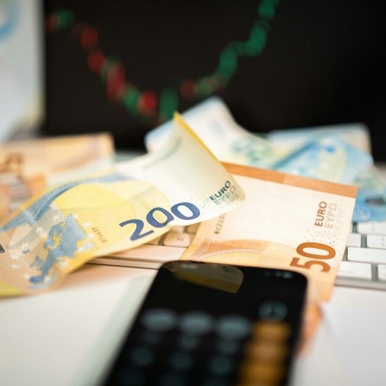 Euroscheine in verschiedenen Werten liegen auf einem Tisch neben einem Taschenrechner.